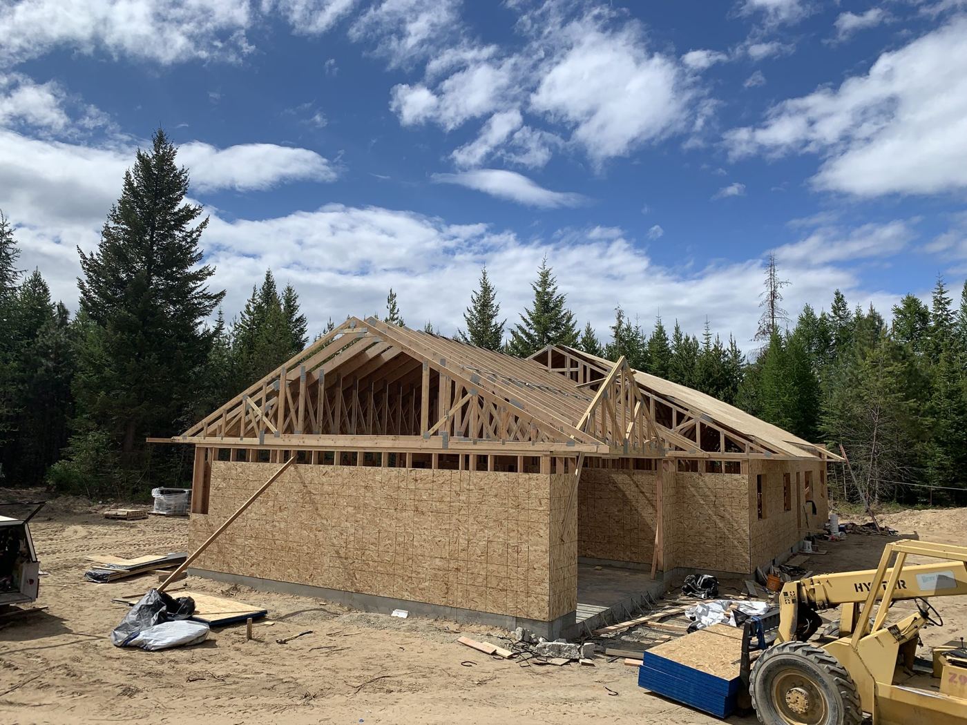 A framed house with roof structure and a loader on site