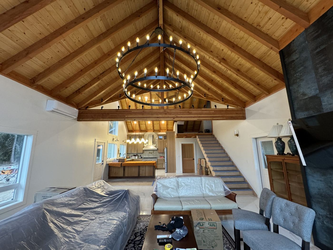 Great room with exposed trusses, wood ceiling and open stair
