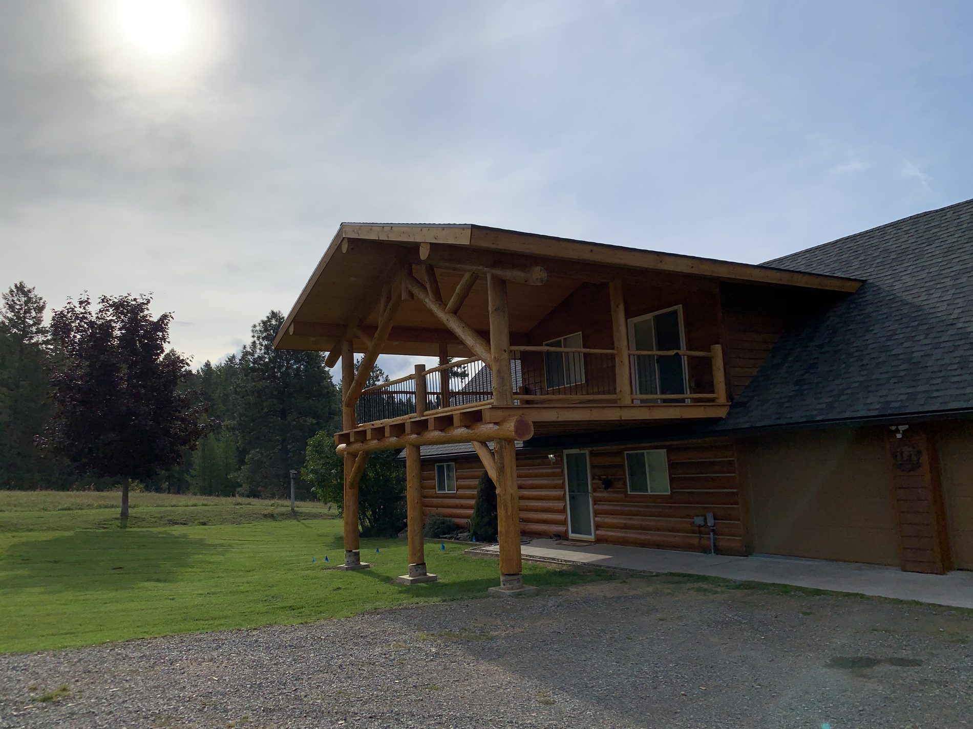Log lodge with a timber-framed entry and green standing-seam roof, built by DeGroff Construction