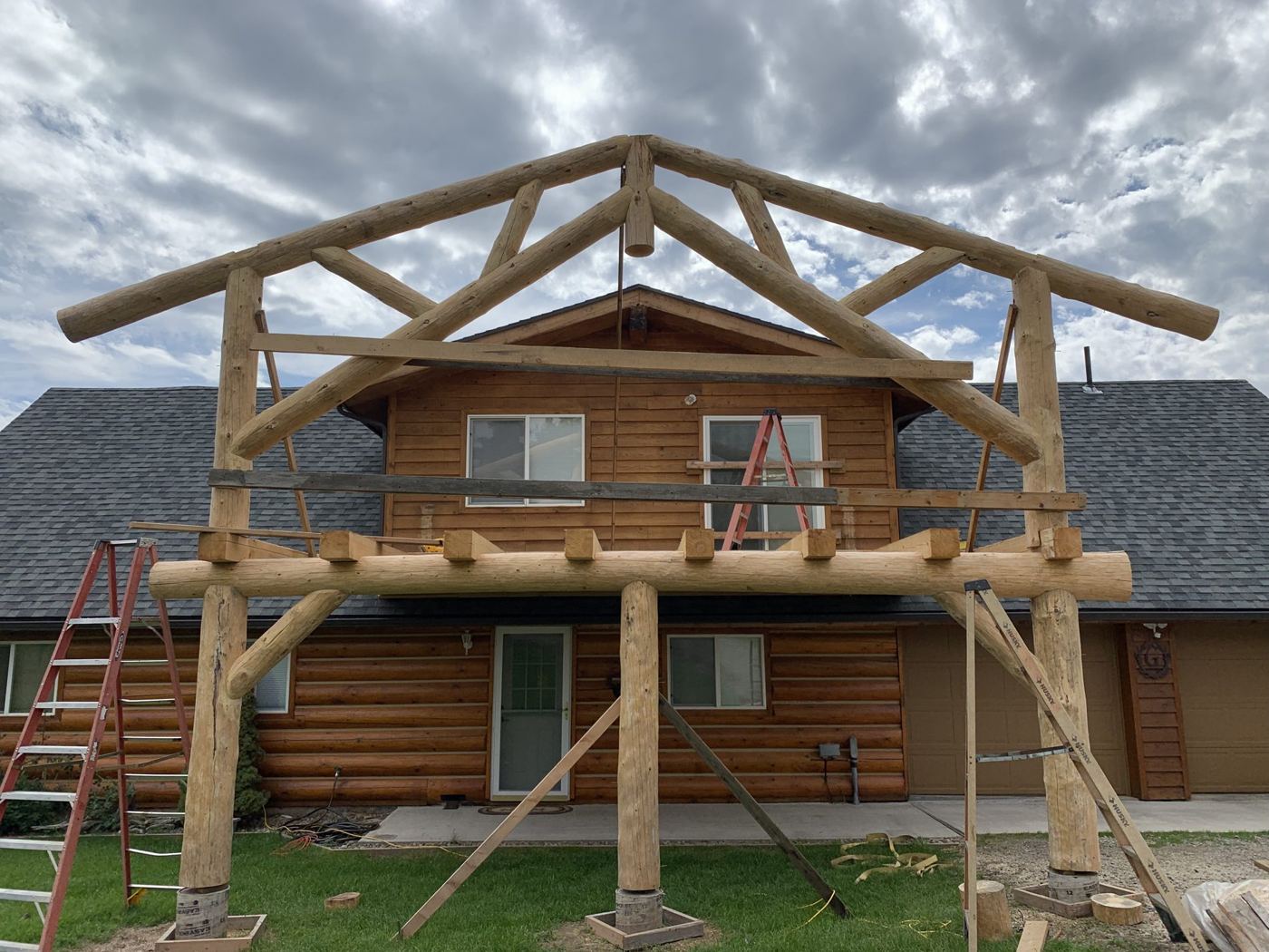 Timber frame gable going up against a log home