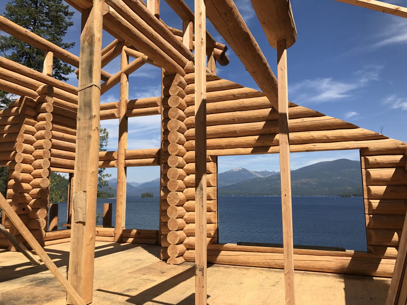 Log walls going up with timber posts and a lake beyond