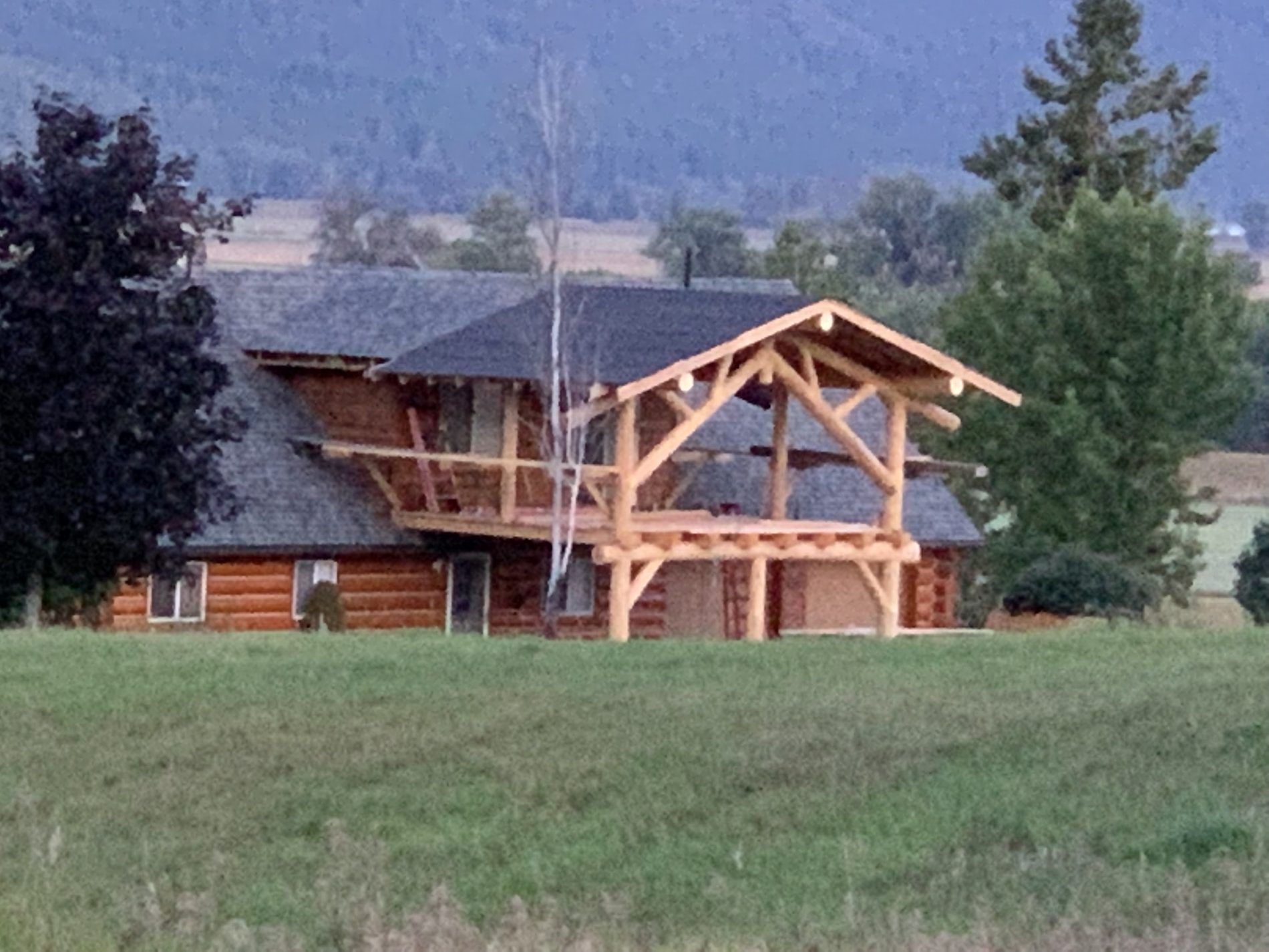 Timber entry structure under construction on a log home with a valley behind